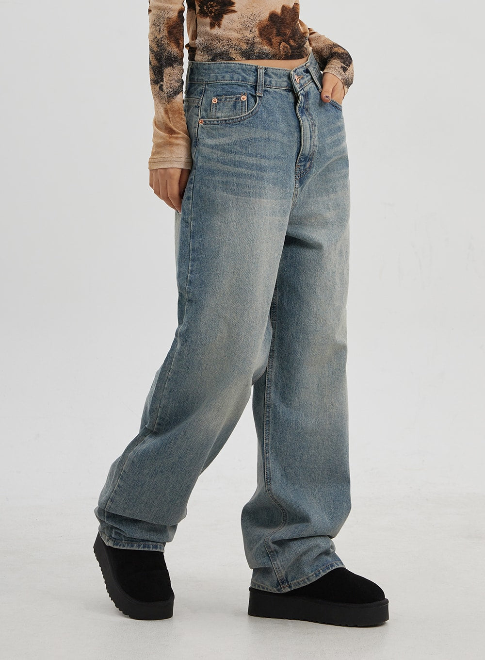 Low Rise Baggy Jeans CJ330 in Blue, angled close-up from waist to hem on model, five-pocket construction with rose-gold rivets, wide-leg faded wash denim pooling at ankle.