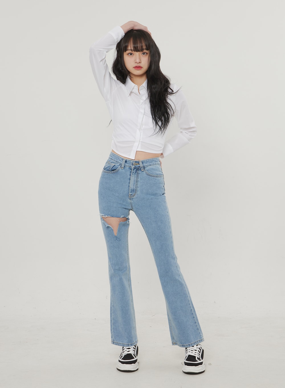Ripped Bootcut Jeans BF306 in light blue, front full-body on model with arms raised, destroyed thigh cutout and slim bootcut flare visible, paired with white crop shirt and sneakers.