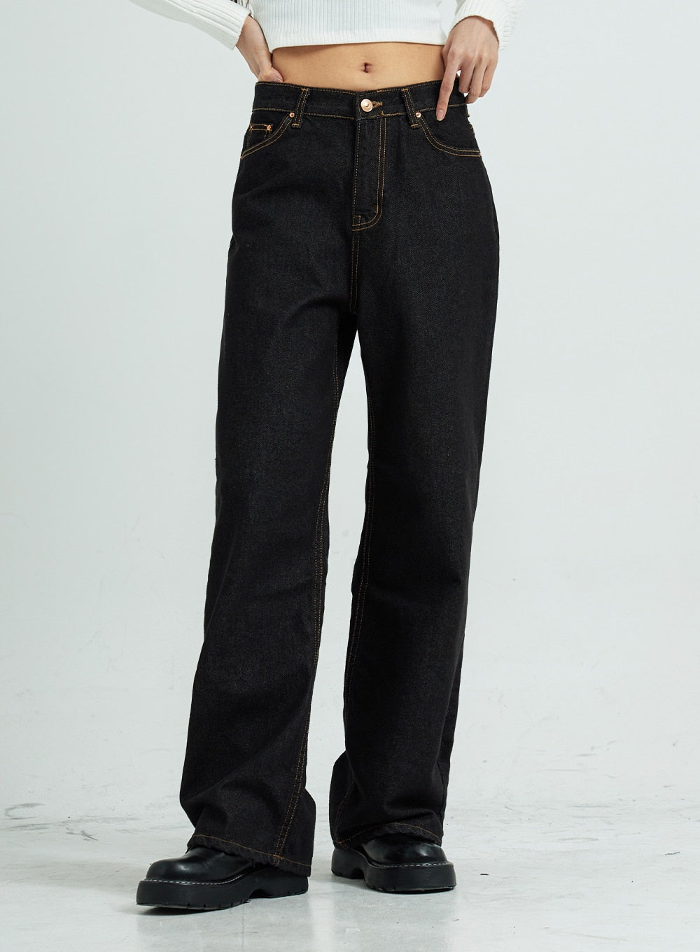 Pepe Wide Pants CS15 in black, front mid-shot on model, wide-leg cotton denim with copper-tone hardware and contrast stitching detail at waistband, paired with white ribbed crop top.