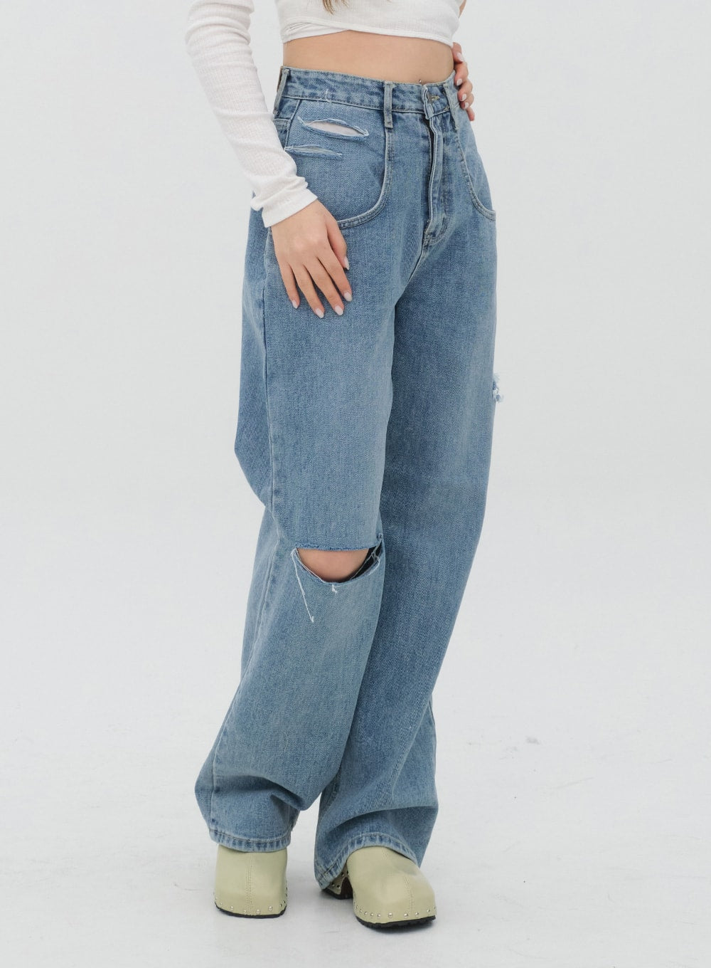 Torn Wide Leg Jeans C1002 in light blue, side close-up waist-to-ankle on model, large knee cutout and slash waistband detail highlighted, wide cotton leg, green clogs.