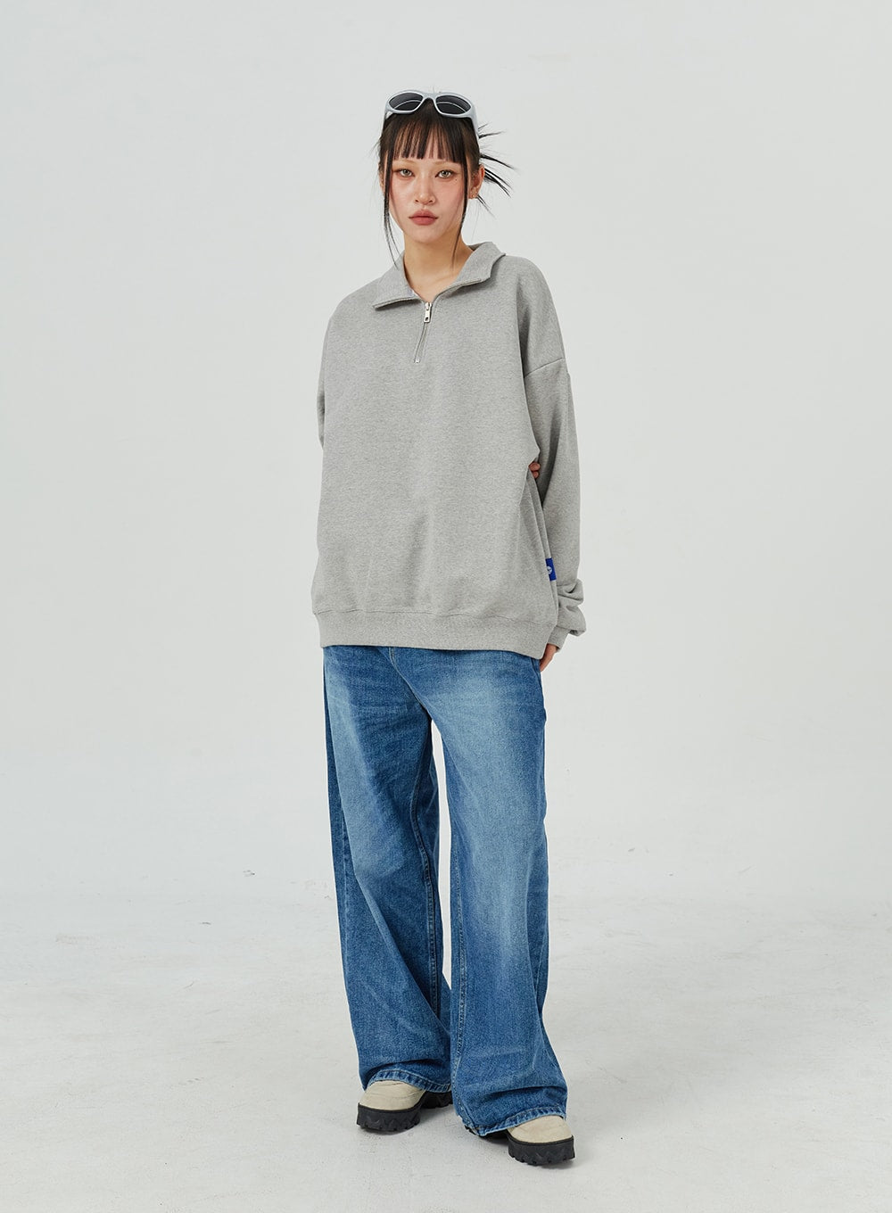 Oversized Jeans Unisex CM321 in blue, full-length front on model, wide-leg faded denim floor-grazing hem, styled with grey half-zip sweatshirt and chunky sneakers.