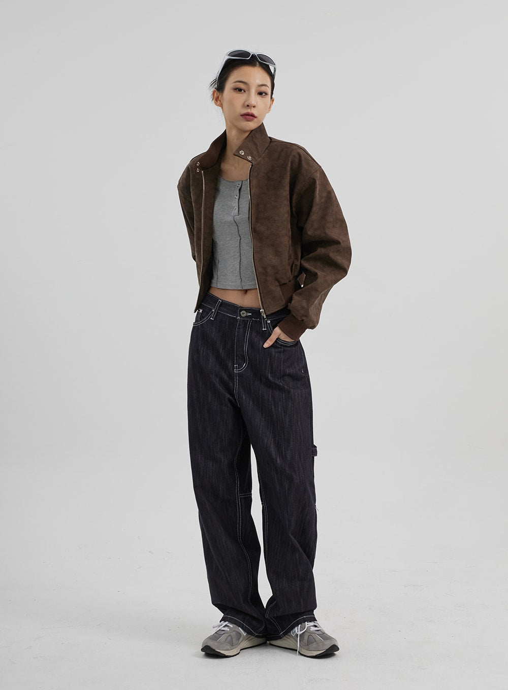 Mid-Rise Baggy Jeans CF307 in dark indigo, full-body front view on model, wide-fit carpenter denim with contrast topstitching, styled with open brown suede bomber and grey ribbed crop top.