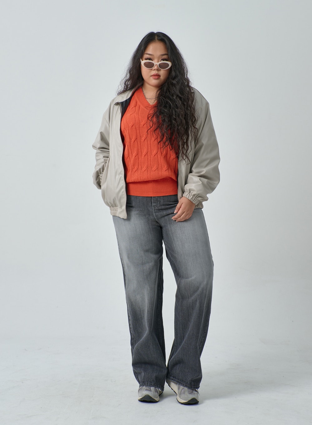 Plus Light Wash Wide Leg Jeans IF317 in grey wash, full-body front on plus-size model with sunglasses, wide leg faded denim, styled with open beige bomber jacket, orange cable-knit sweater and sneakers.