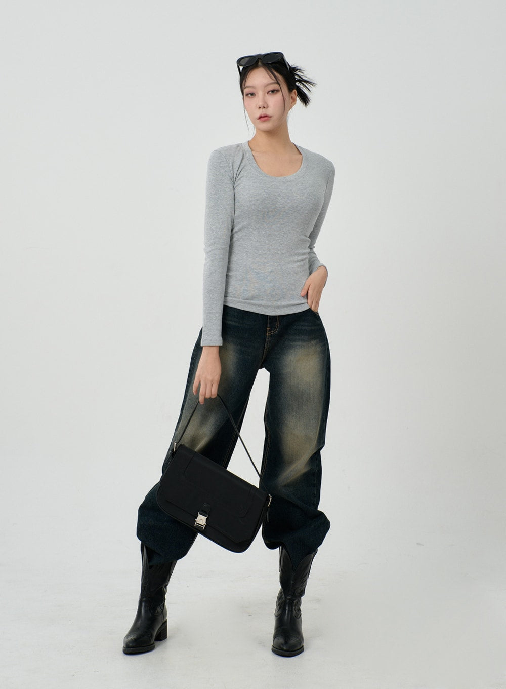 Vintage Washing Baggy Jeans ID23 in dark indigo, full-body front on model holding black crossbody bag, baggy wide-leg denim with strong vintage fade, styled with grey fitted top and black knee boots.