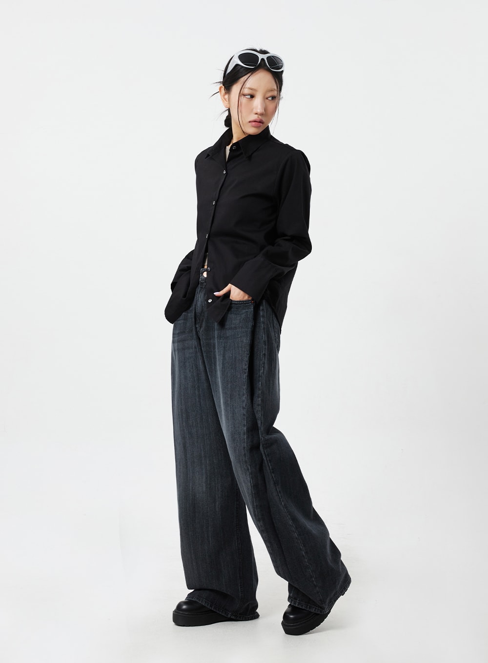 Mid-Rise Baggy Jeans CM324 in washed black denim, full-body angled view on model with hand in pocket, relaxed street-style wide leg, worn with black button-up shirt.
