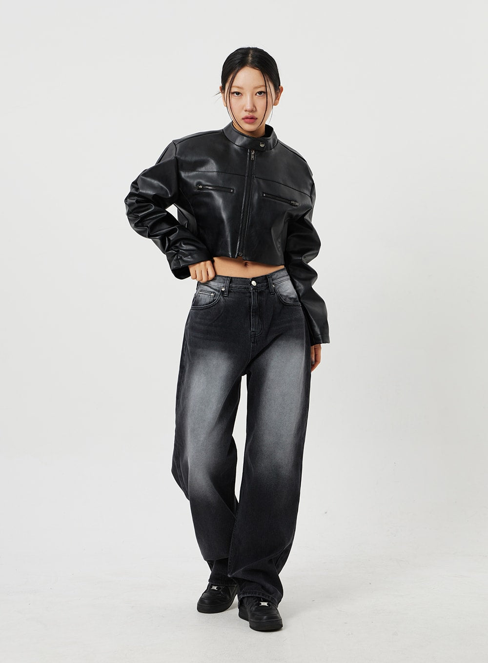 Mid-Rise Baggy Jeans CF328 in black, front full-length shot on model with hand on hip, wide-fit faded denim, mid-rise waist, styled with cropped faux-leather jacket and black sneakers.