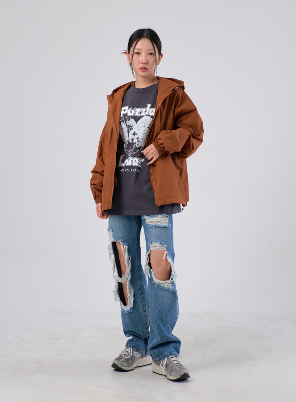 Ripped Knee Jeans IA305 in medium blue, full-body front on model in straight stance, wide-leg cotton denim with open ripped knees layered under an open brown hooded jacket and graphic tee.