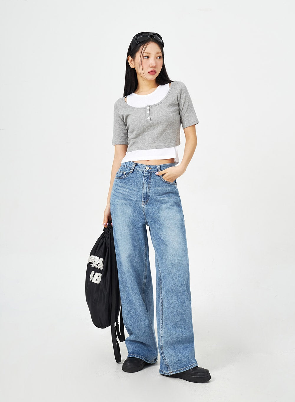 Mid-Wash Bootcut Jeans CM323 in mid blue, full-length front view on model with bag at side, wide-fit high-rise washed denim bootcut jeans with hand in pocket, casual styling.