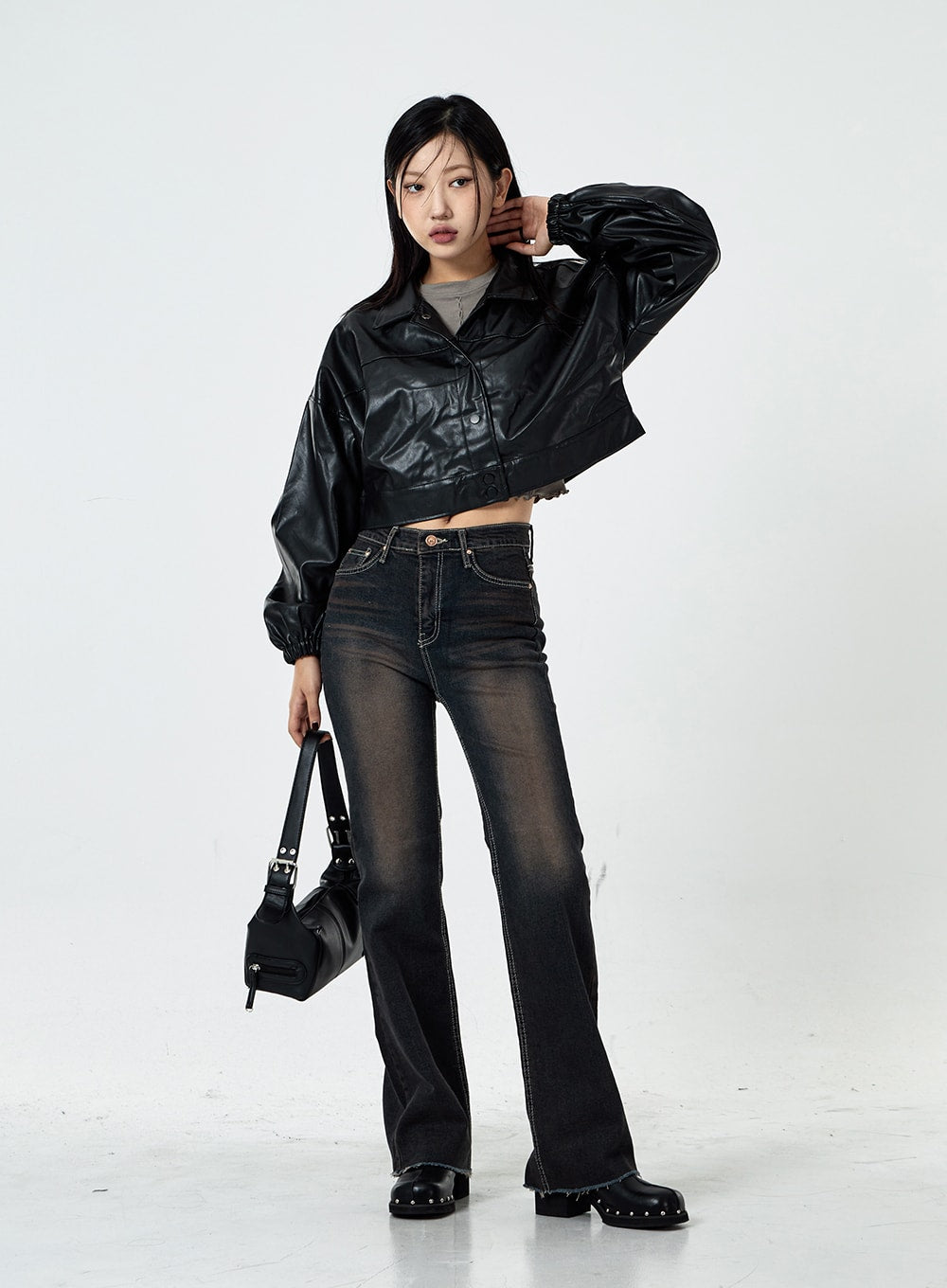 Basic Washed Bootcut Jeans CS07 in black washed denim, full-length front view on model, slim bootcut flare, high-waist, dynamic pose with arm raised, styled with crop leather jacket and bag.