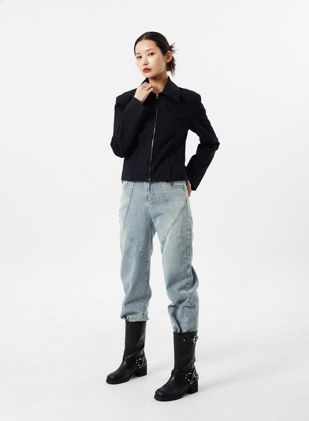 Light Wash Straight Leg Jeans CM307 in light blue, full-body front on model with hand-to-chin pose, straight-fit washed denim with geometric seam lines, layered with black cropped jacket and boots.