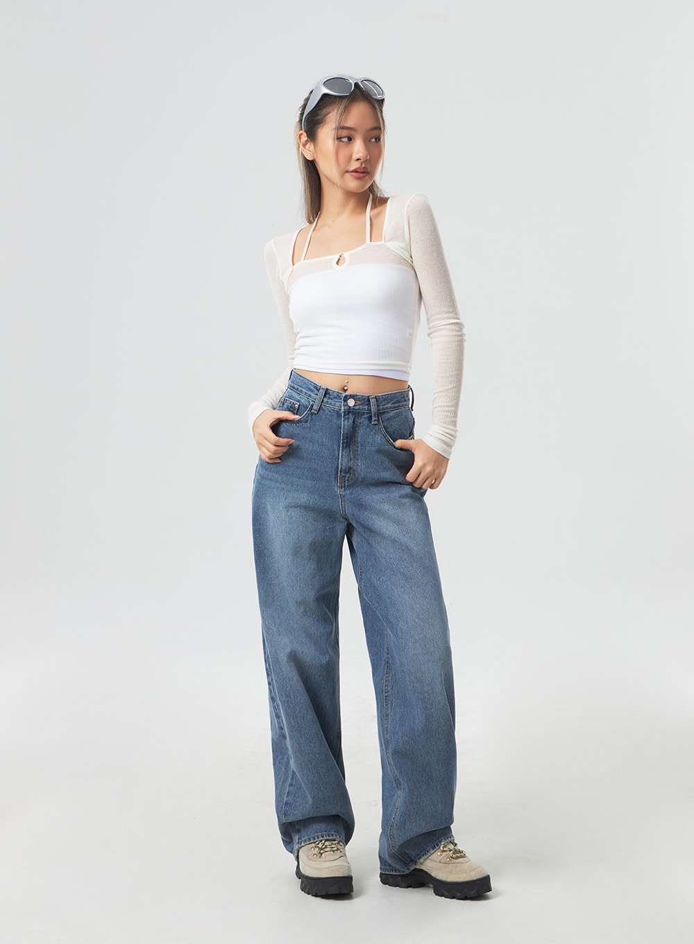 Wide Leg Mid-Wash Jeans CM331 in mid-wash blue, three-quarter front view on model looking to side, hands in front pockets, wide-leg high-rise denim, casual styling with mesh crop top.