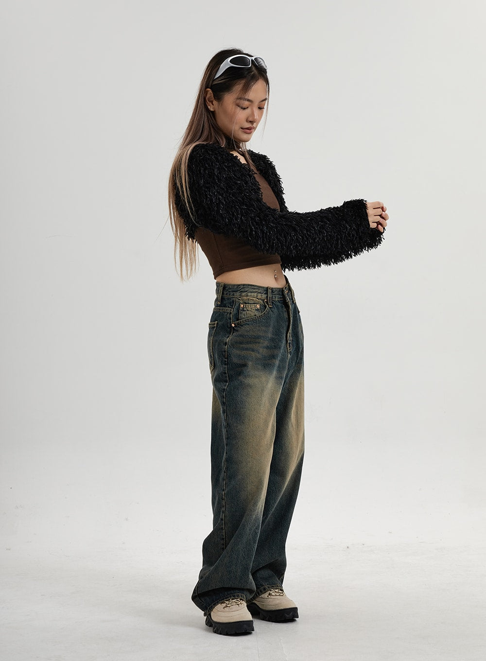 Vintage Washing Wide Leg Denim Pants CN14 in vintage washed indigo, full-body side profile on model looking down, wide-fit denim with dusty yellow fade pooling at hem, styled with black fluffy cardigan.