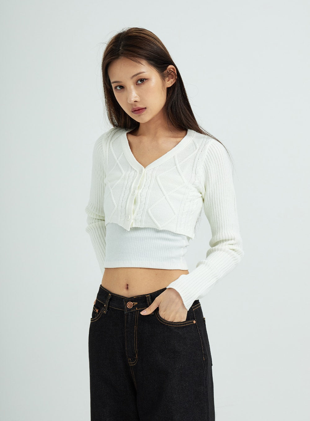 Pepe Wide Pants CS15 in black, upper-hip close-up on model, wide-leg cotton denim with gold contrast topstitching at waistband, hand in pocket, paired with white cropped knit top.