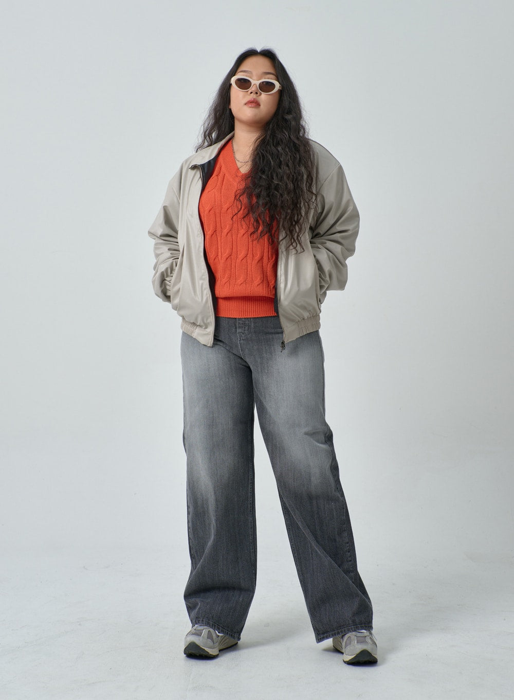 Plus Light Wash Wide Leg Jeans IF317 in grey wash, full-body front standing pose on plus-size model, wide leg cotton denim with gradient wash, hands-behind-back stance, styled with beige bomber and orange sweater.