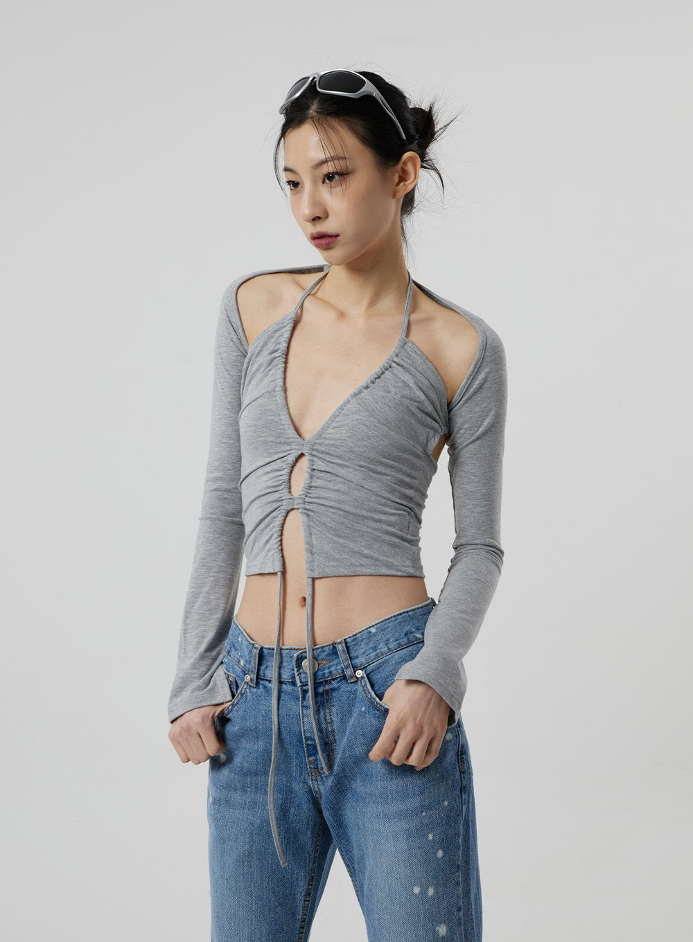 Low Rise Bootcut Jeans CF309 in blue denim, upper-body focus on model, low waist with front button fly and paint-splatter detail visible, styled with grey long-sleeve ruched halter crop top, waist area emphasis.