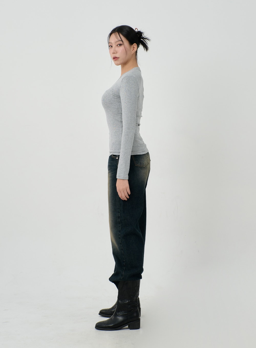 Vintage Washing Baggy Jeans ID23 in dark indigo, full-body side profile on model, wide-leg silhouette tapering at hem over black boots, vintage yellow-tinted wash on thighs, grey ribbed top.