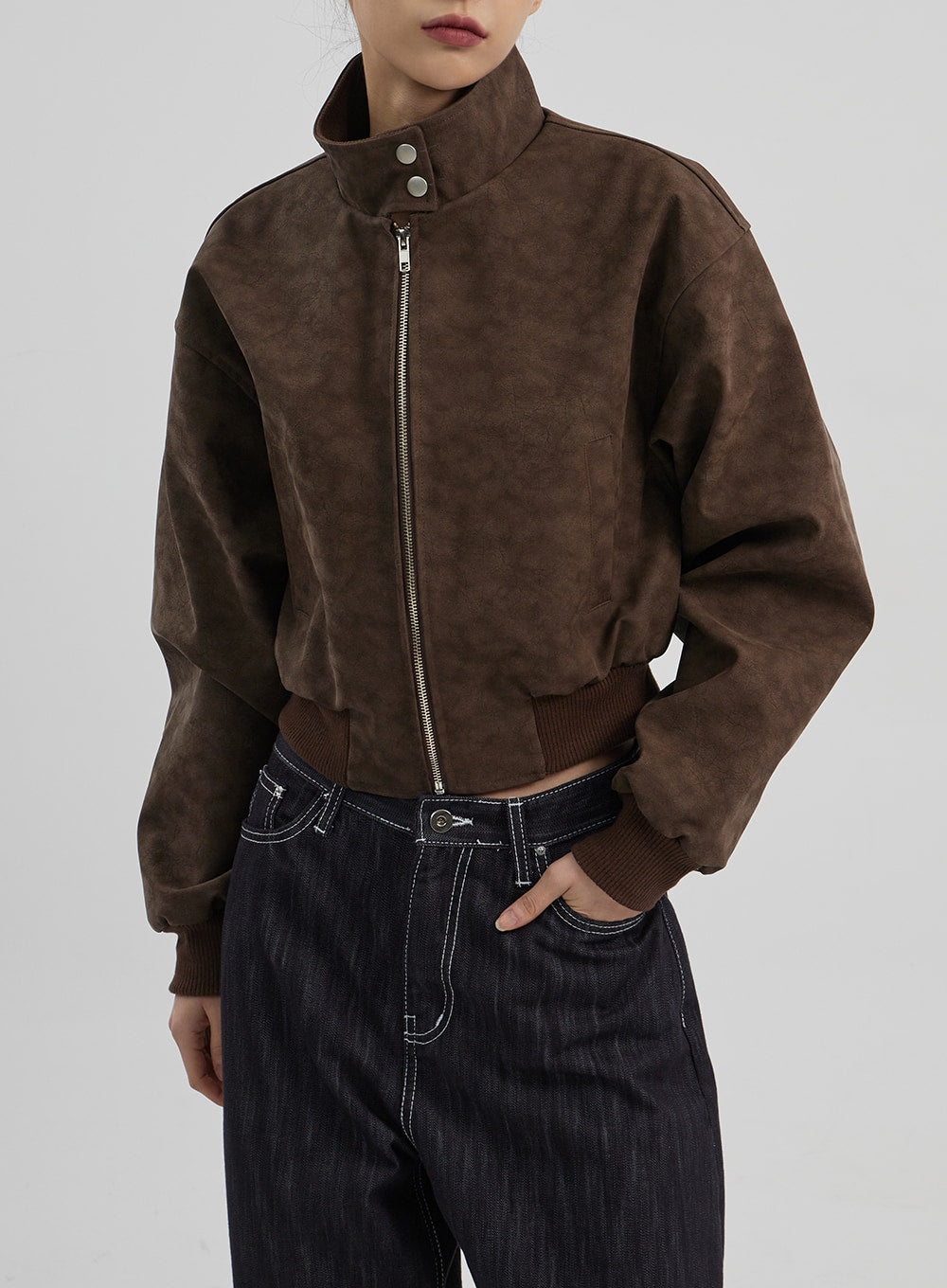 Mid-Rise Baggy Jeans CF307 in dark indigo, upper waistband detail close-up on model, mid-rise front pockets with white contrast stitching and silver hardware visible beneath brown cropped jacket.