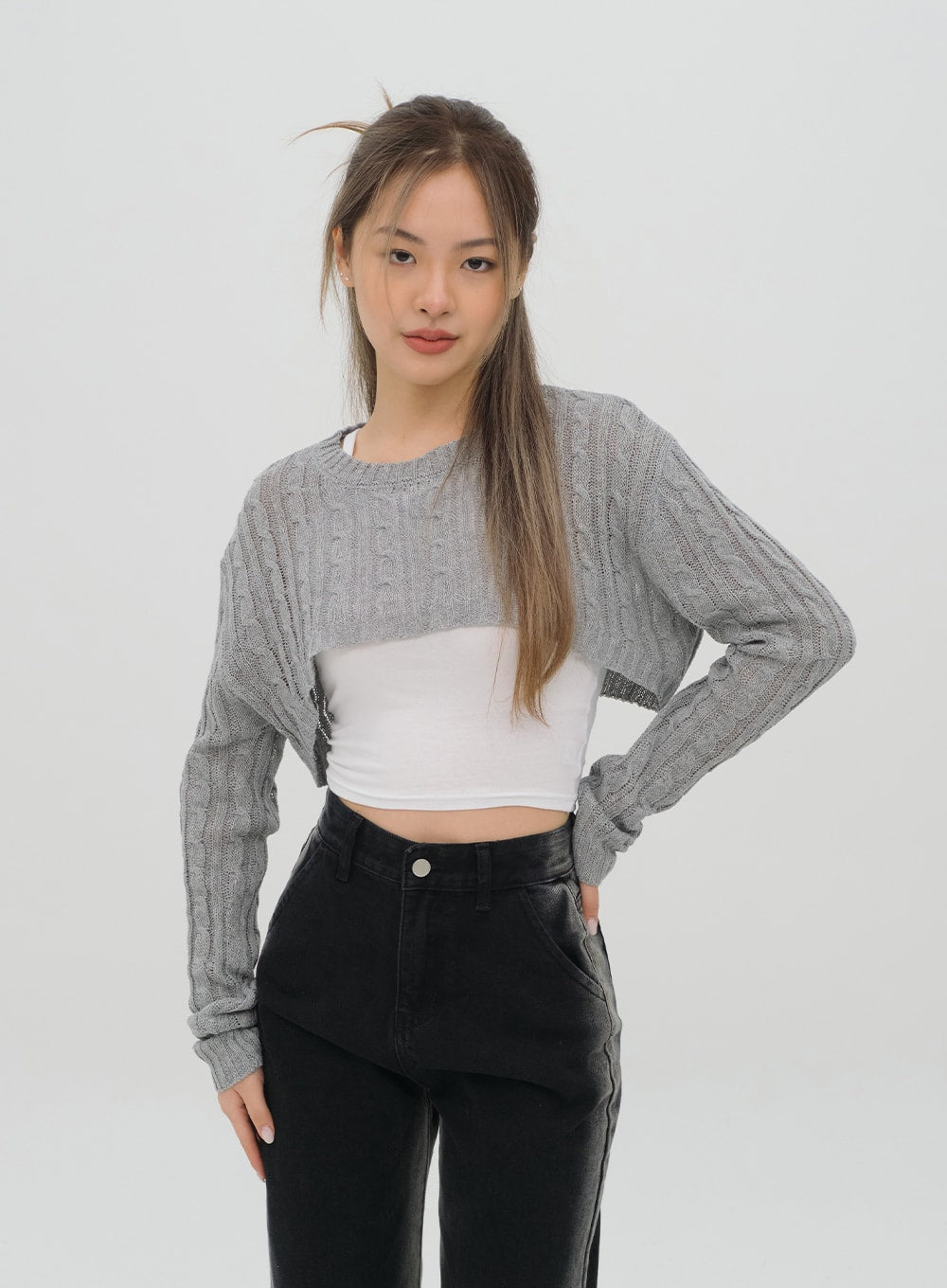 Black Jeans C1002 in washed black, upper-body front shot on model hand on hip, high-rise waistband and front pockets visible, wide-fit denim, paired with grey cable-knit crop over white top.