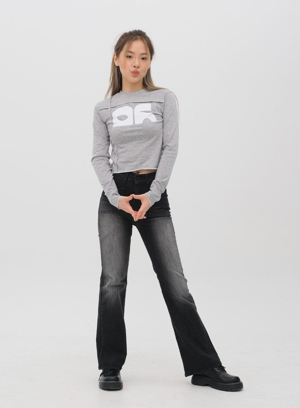 Bootcut Jeans M4 in black gradation wash, full-length front view on model in playful pose, long bootcut flare, high waist, gradation wash denim, street style outfit.