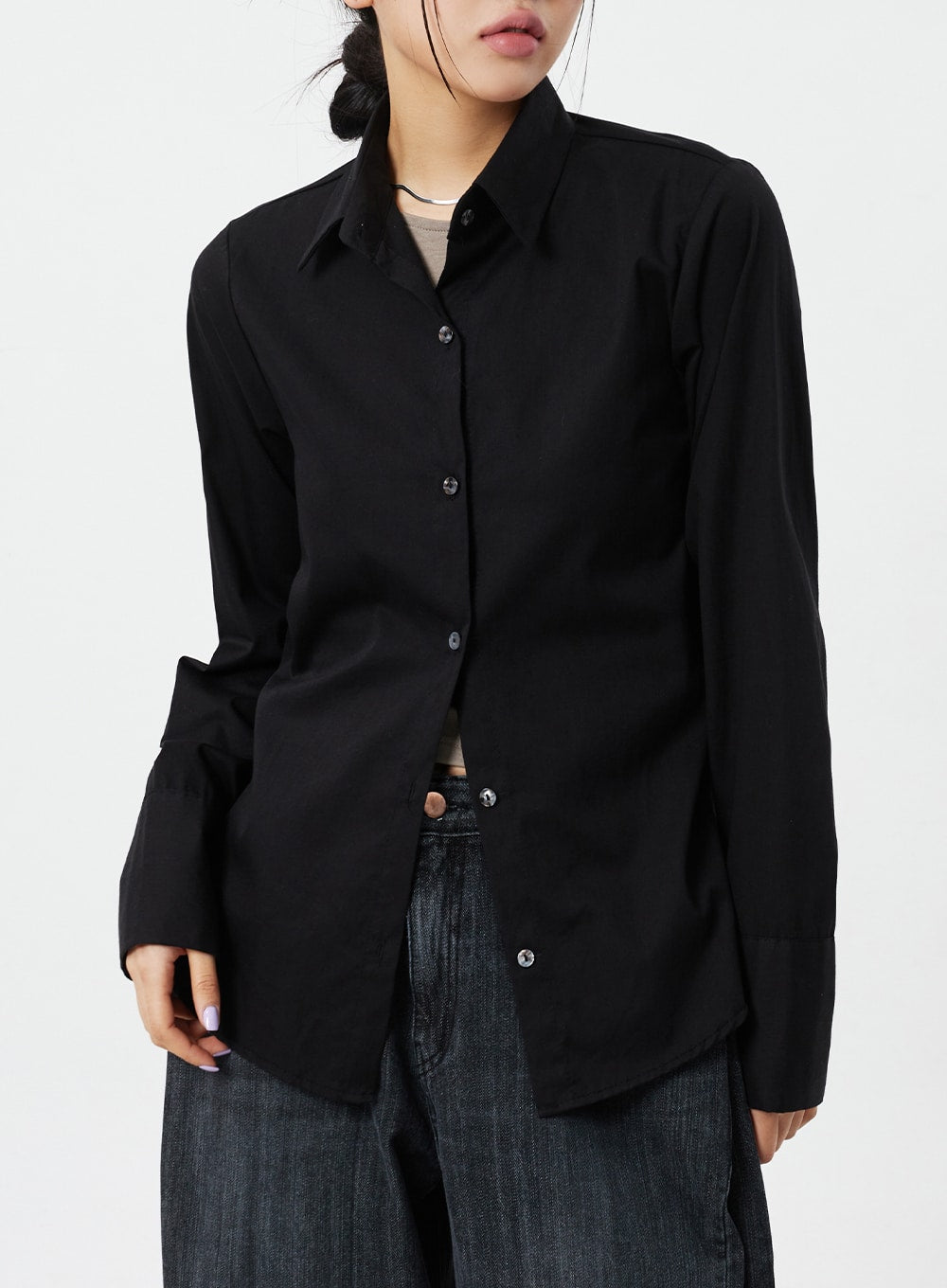 Mid-Rise Baggy Jeans CM324 in washed black denim, upper hip close-up on model, waistband and top of wide-leg denim visible beneath black overshirt hem, faded cotton texture.