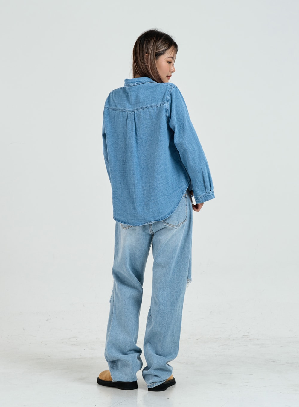 Ripped Maxi Denim Pants Unisex CO14 in light blue, back full-body view on model, wide-leg cotton denim with subtle rip visible at lower hem, styled with oversized denim shirt.