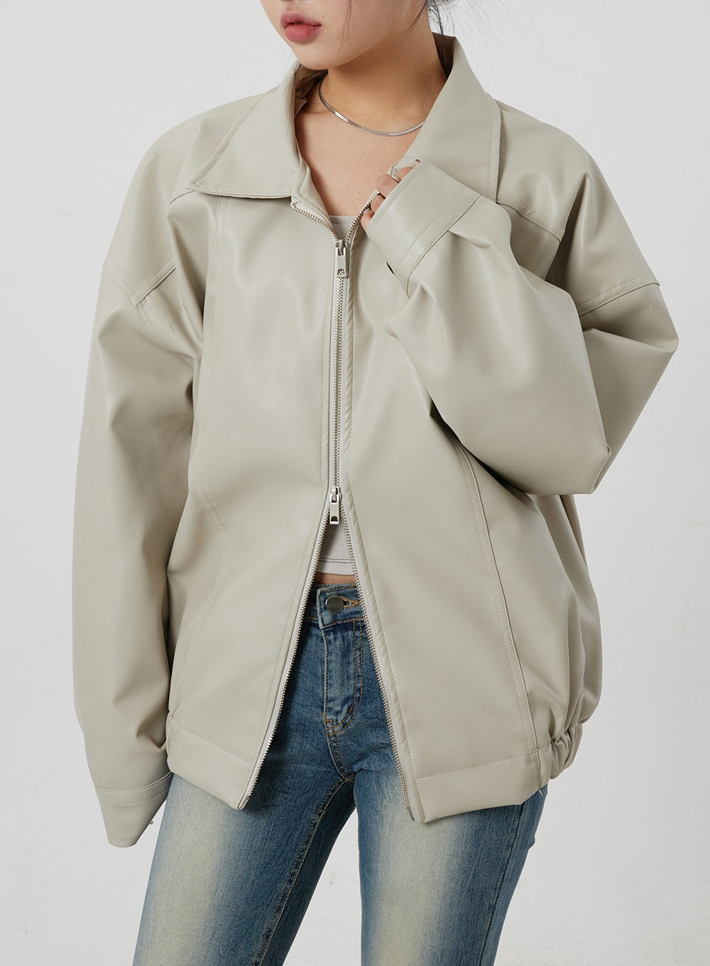 Low Rise Bootcut Jeans CF302 in blue, upper waistband close-up on model, low-rise button waist peeking under open beige jacket, vintage-wash denim texture visible.