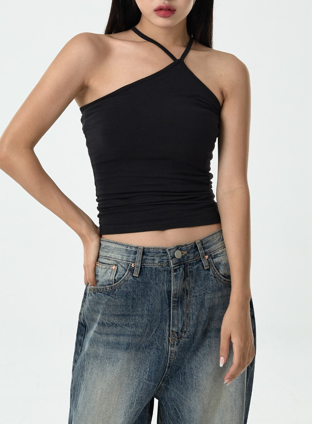 Washed Denim Pants CG10 in dark blue, upper-body and waistband close-up on model, mid-rise front pockets with washed denim texture visible, styled with black asymmetric halter crop top.
