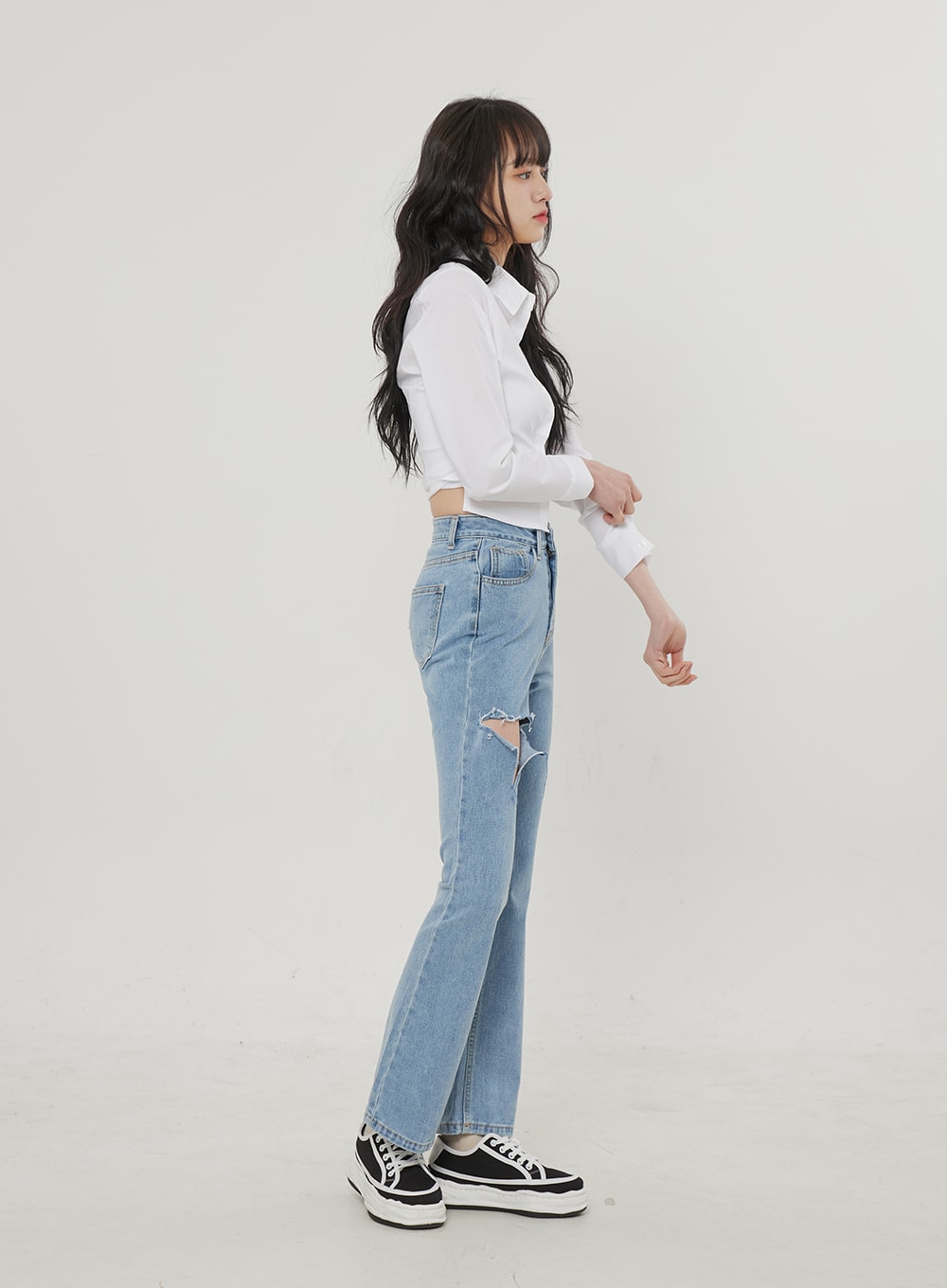 Ripped Bootcut Jeans BF306 in light blue, side profile full-body on model, slim-fit high-rise silhouette with frayed thigh rip detail, paired with white crop shirt and chunky sneakers.