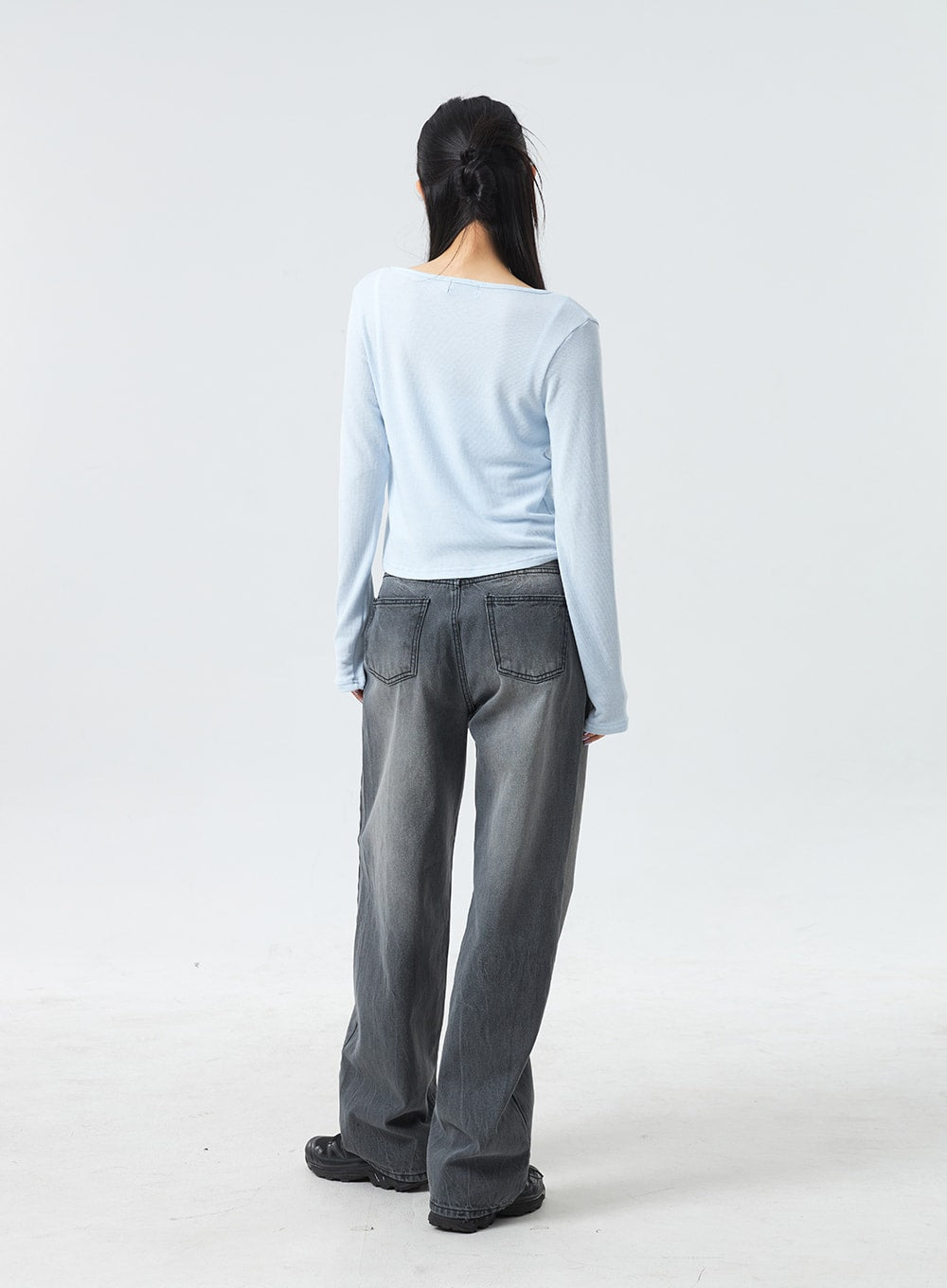 Low Rise Mid-Wash Jeans CM327 in grey, full-length back shot on model, two back patch pockets, wide-leg cotton denim with grey mid-wash fade, low-rise silhouette, paired with light blue top.