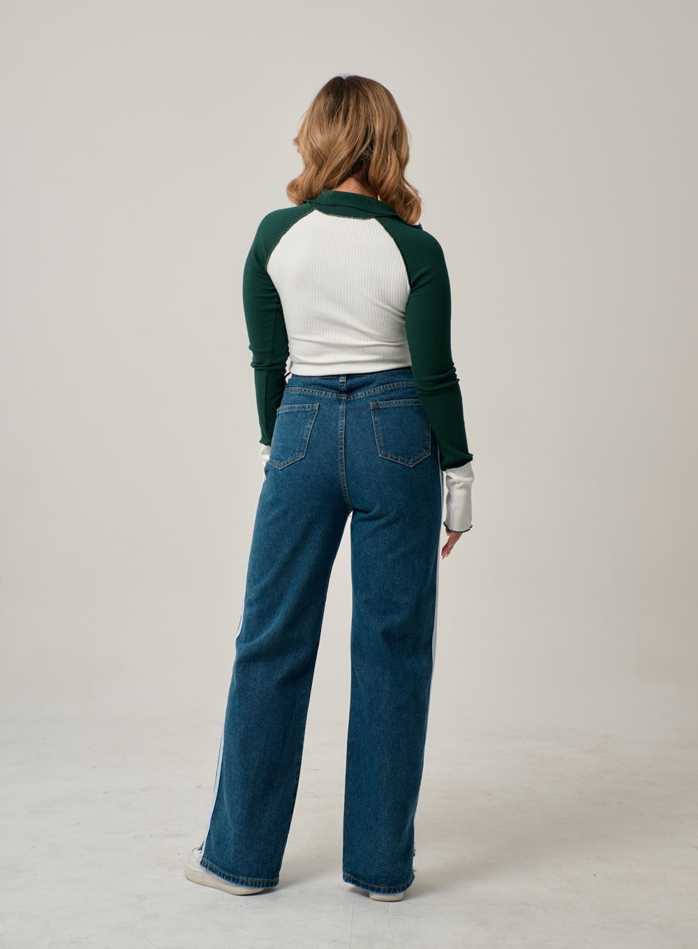Side Stripes Straight Leg Jeans IN22 in mid blue, back full-length shot on model, high-rise wide-fit denim with back pockets and white side stripes at hem edges, paired with colorblock ribbed top.