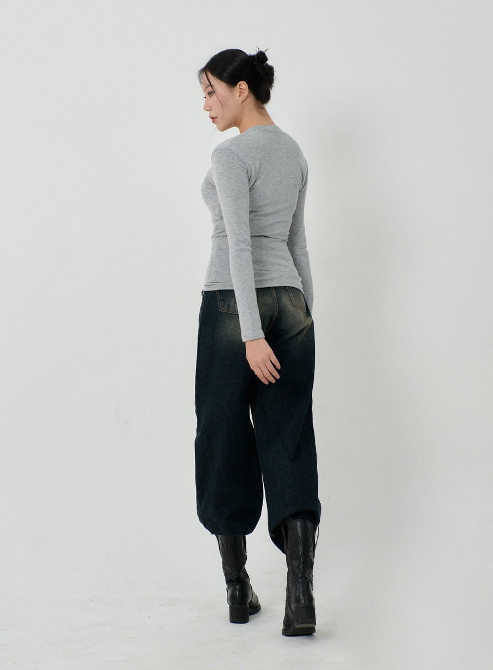 Vintage Washing Baggy Jeans ID23 in dark indigo, back three-quarter view on model, back pockets with vintage wash fading, voluminous baggy leg, paired with grey long-sleeve top and black knee boots.