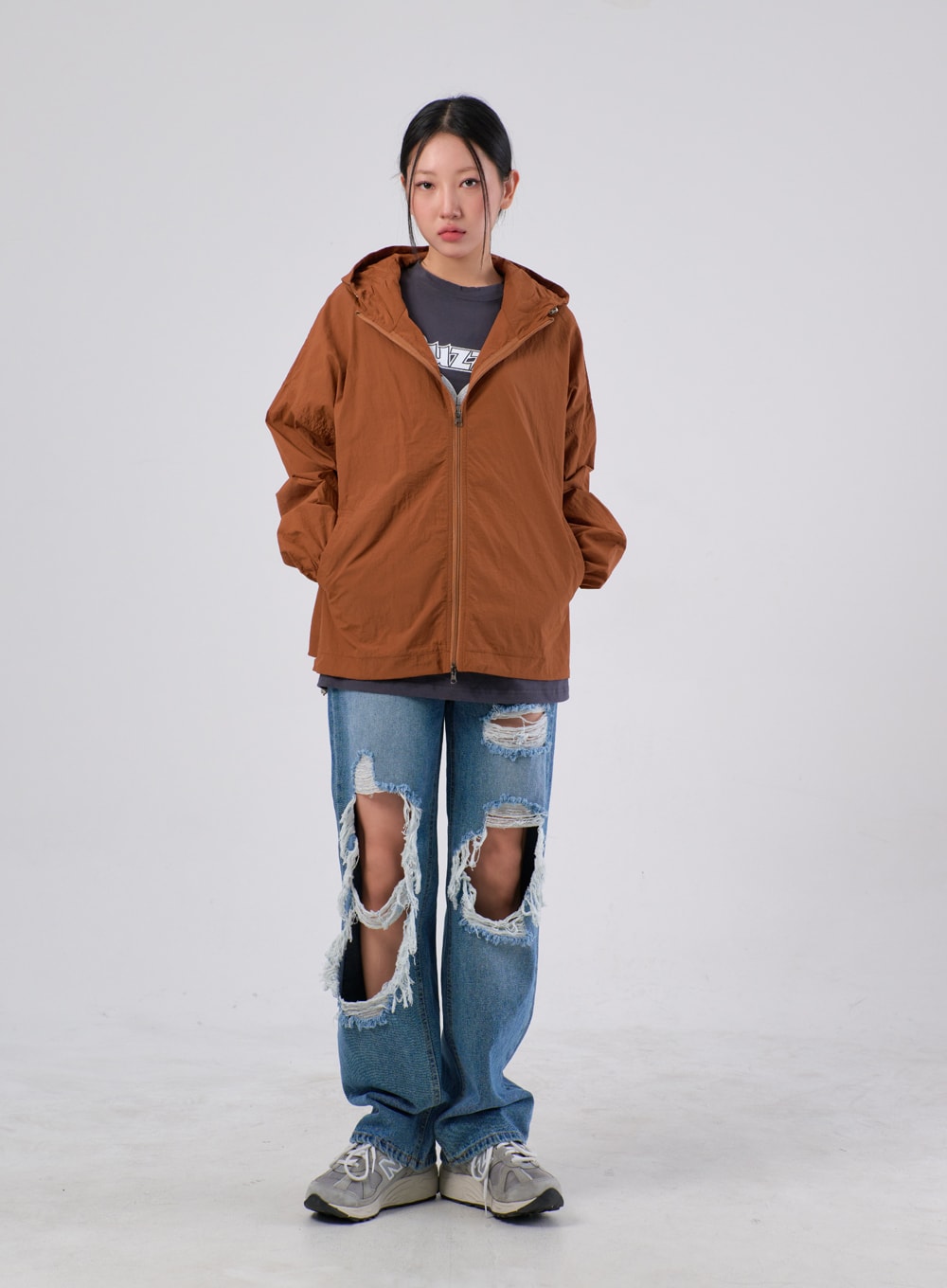 Ripped Knee Jeans IA305 in medium blue, full-body front on model, wide-fit street denim with large frayed knee rips, styled with a zipped brown hooded jacket layered over grey tee.