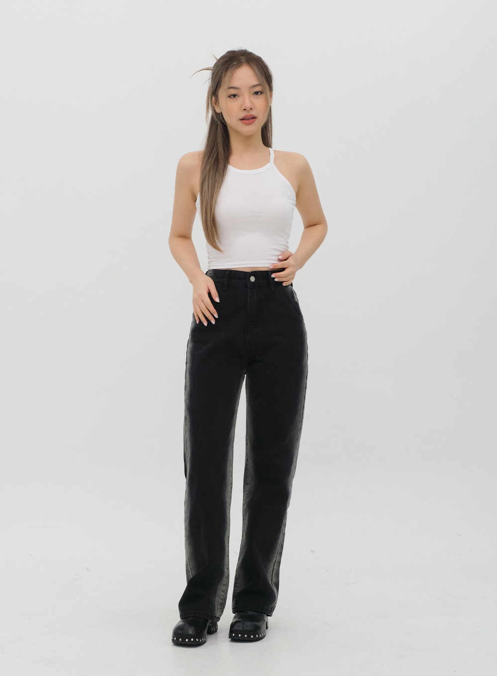 Black Jeans C1002 in washed black, full-body front shot on model in white halter crop top, high-rise wide-leg long cotton denim with subtle wash fade, button closure, street style look.