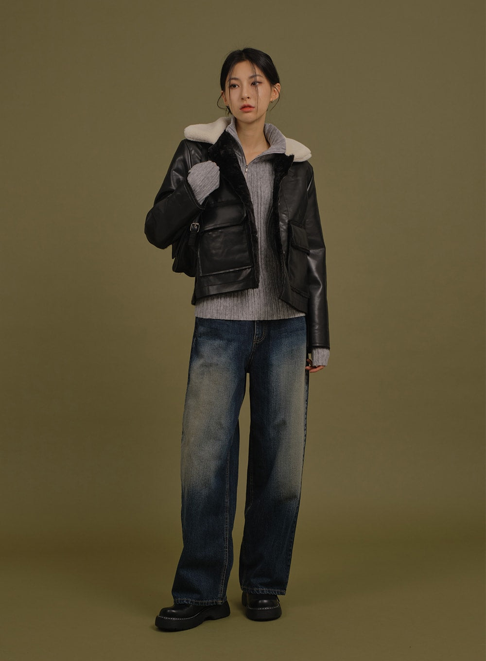 Washed Wide Denim Pants in blue, full-body front shot on model holding bag, wide straight leg with washed gradation, layered under black leather jacket and grey knit.