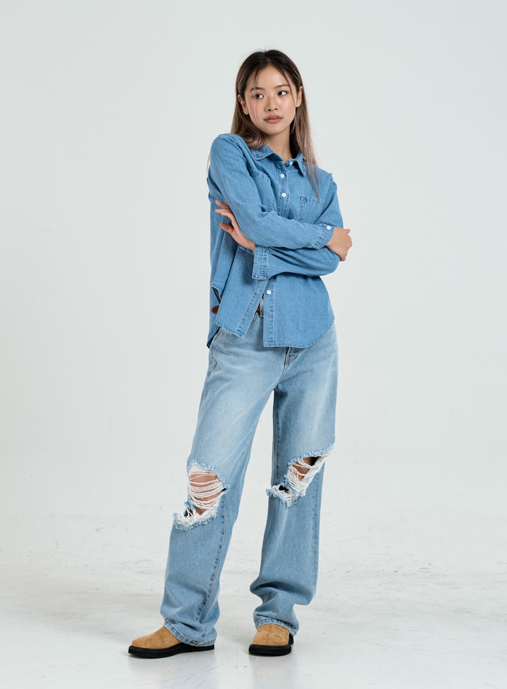Ripped Maxi Denim Pants Unisex CO14 in light blue, full-body front view on model with arms crossed, wide-fit destroyed denim with large frayed knee rips, paired with denim shirt.