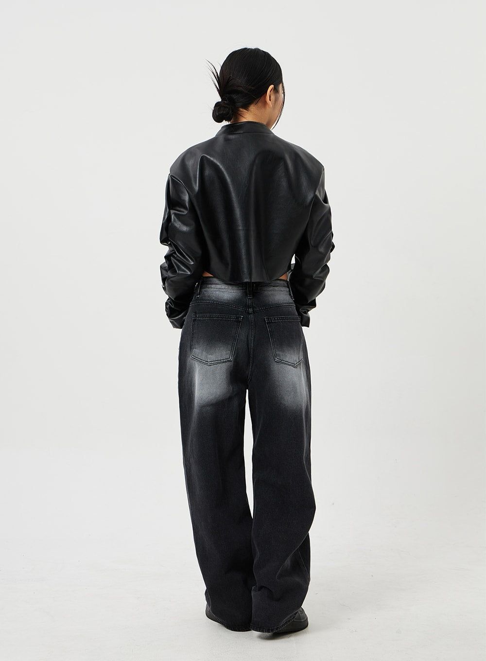 Mid-Rise Baggy Jeans CF328 in black, back full-length view on model wearing cropped faux-leather jacket, wide-fit faded denim with back patch pockets and washed gradient from waist to hem.