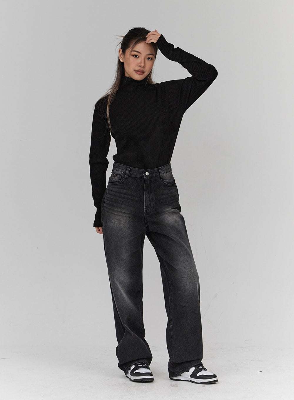 Light Washing Wide Leg Black Jeans CN23 in washed black, full-length front view on model, wide leg washed cotton denim, model posing with hand raised, styled with black turtleneck and sneakers.