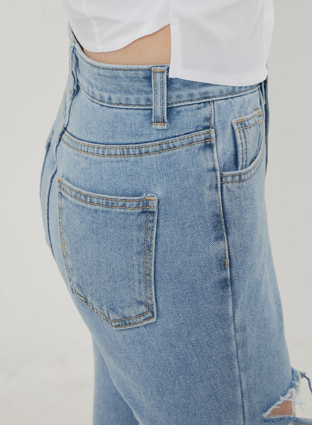 Ripped Bootcut Jeans BF306 in light blue, close-up of back waistband and rear pocket, detailed topstitching on high-rise waistband and patch pocket, light-wash denim texture visible.