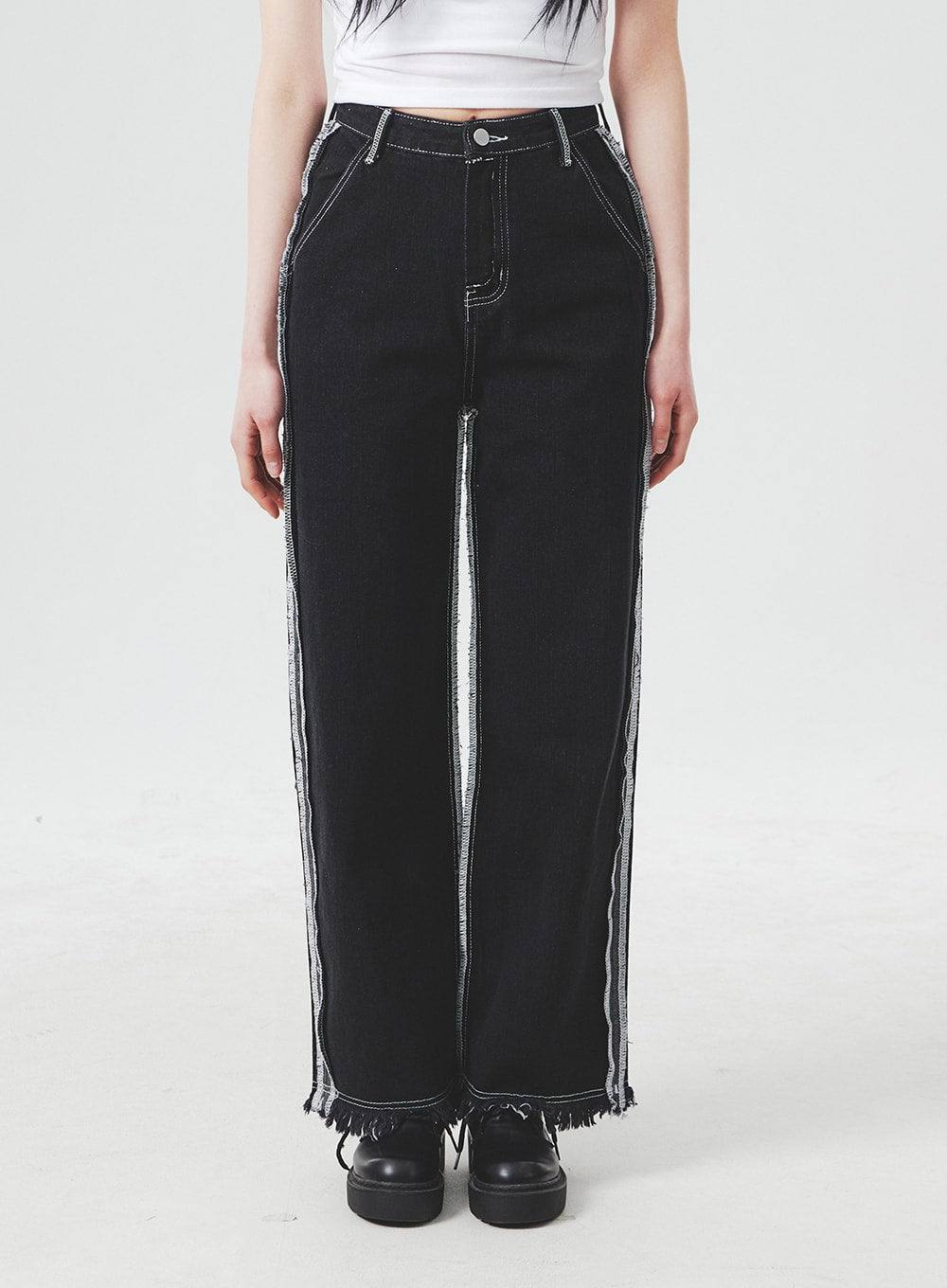 Stitch Detail Jeans BA307 in black, front close-up on model from waist to ankle, wide-fit cotton denim showing contrast stitch side panels, exposed frayed seams, and raw fringe hem.