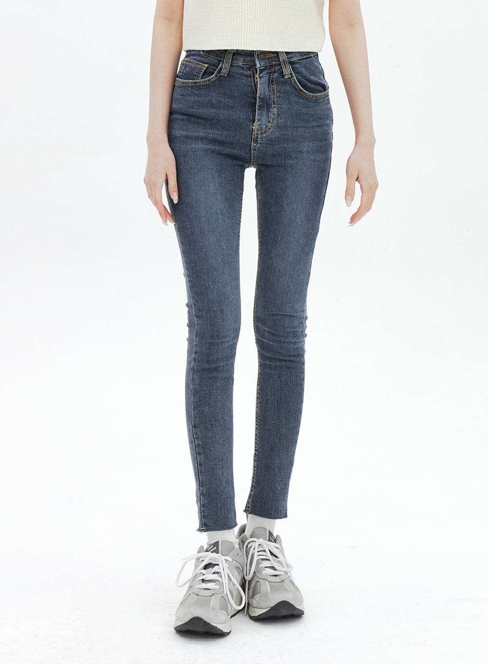 Skinny Ankle Jeans BA321 in dark blue denim, front close-up from waist to ankle on model, high-rise waistband with button fly, slim tapered leg, raw-hem ankle, worn with white sneakers.