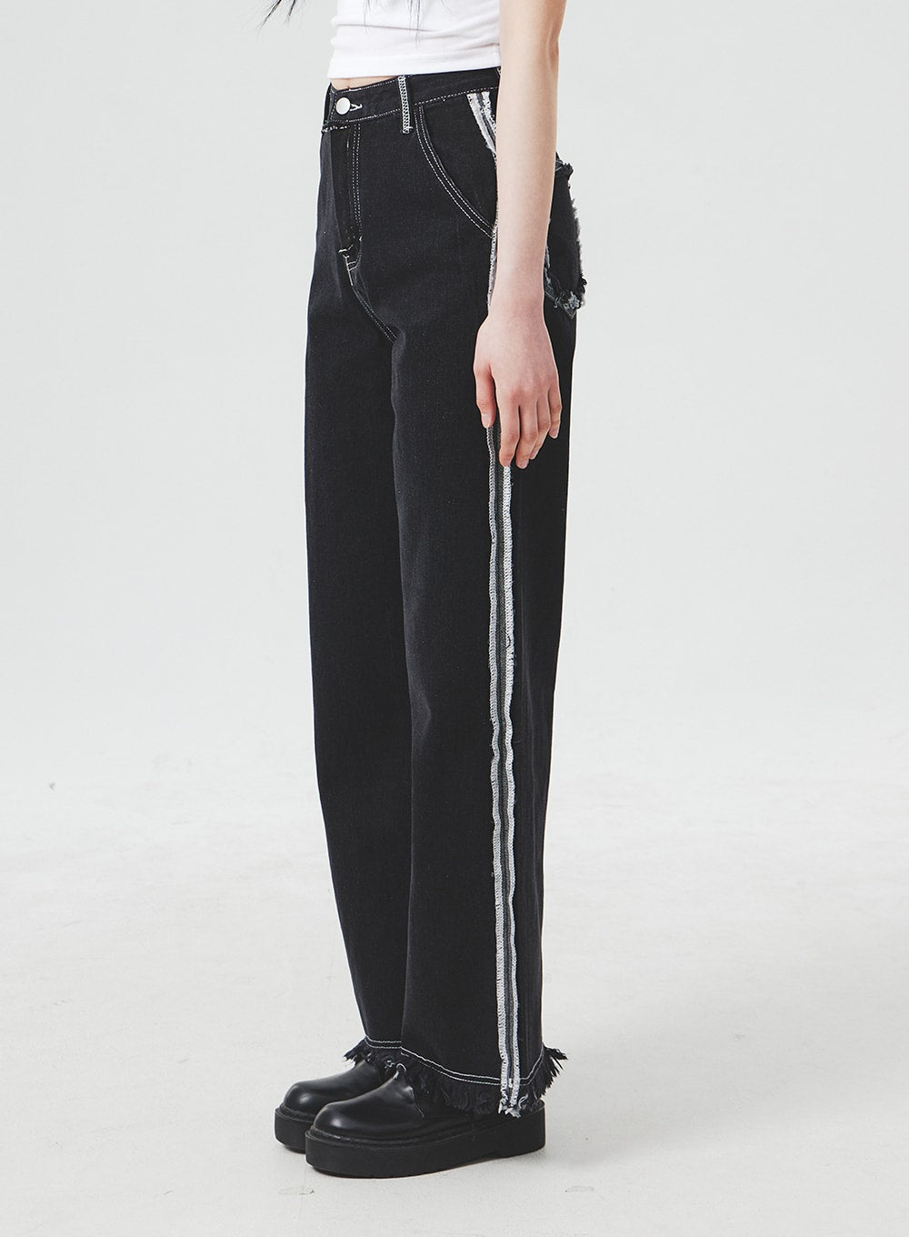 Stitch Detail Jeans BA307 in black, side view on model, wide-fit denim highlighting the vertical contrast stitch stripe along the outer seam and raw fringe hem at the ankle.