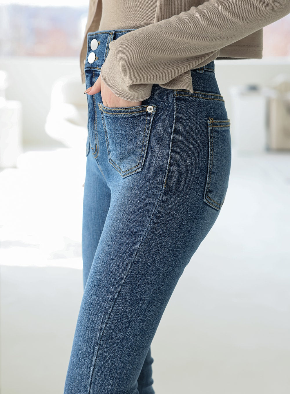 Double Button Raw Hem Skinny Jeans IA11 in mid blue denim, close-up side view of hip and thigh, highlighting double-button high-rise waistband, front and back pocket placement, and stretch denim fit.