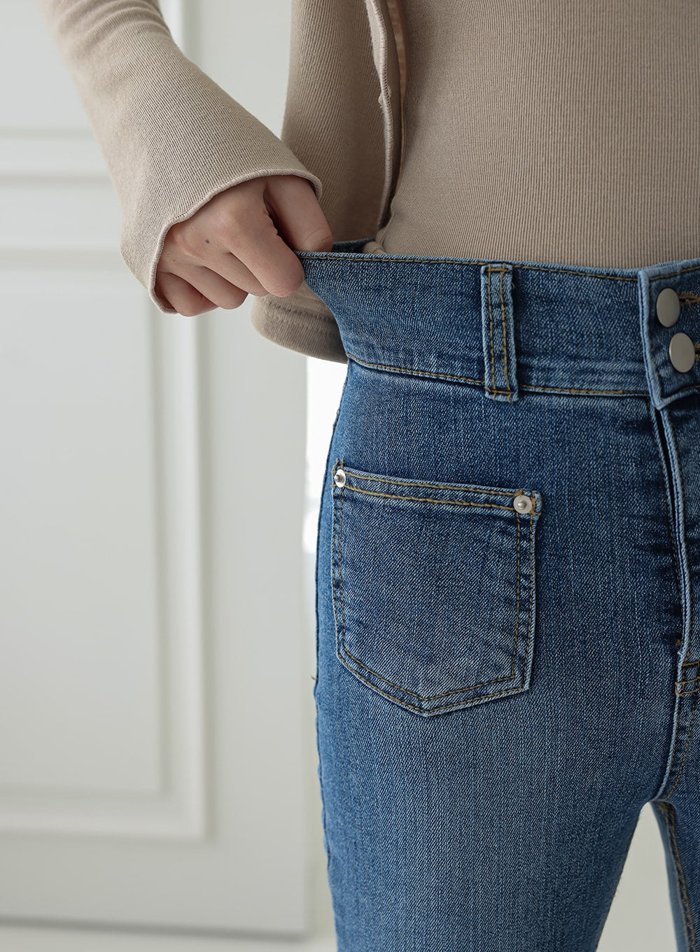 Double Button Raw Hem Skinny Jeans IA11 in mid blue denim, detail close-up of waistband and front pocket, showing double silver buttons, belt loop, patch pocket with topstitching, and denim fabric texture.