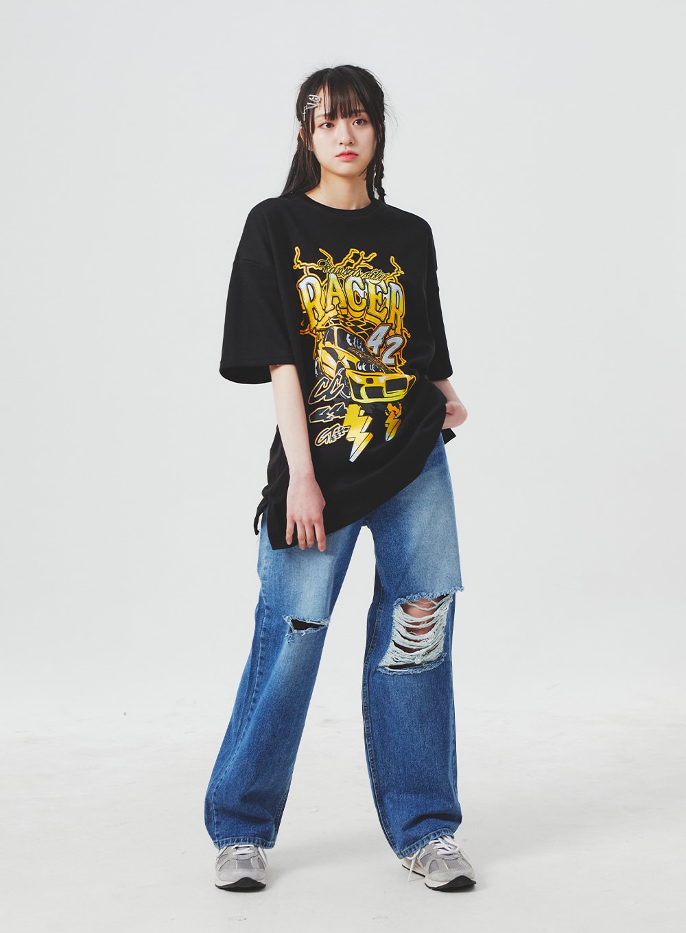 Ripped Knee Blue Jeans BA307 in blue, full-body slight-angle front shot on model, wide-fit denim with destroyed knee cutouts, worn with oversized black graphic tee, casual street style.