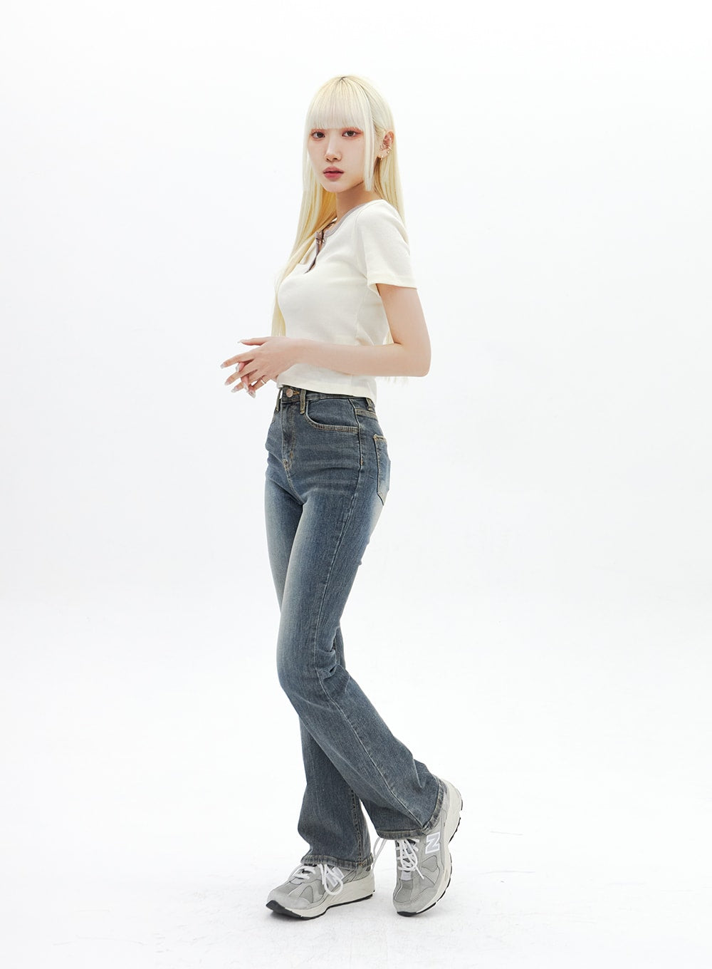 Dark Wash Bootcut Jeans BA320 in dark blue, three-quarter side view on model turning slightly, slim high-rise fit with bootcut hem, washed finish, styled with white crop tee and chunky sneakers.