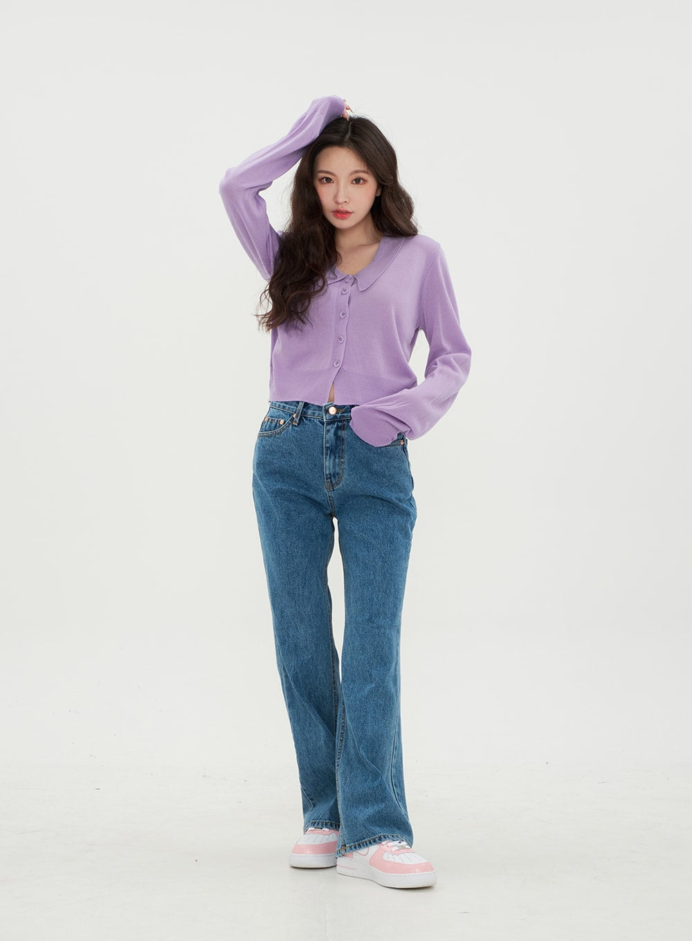 Semi Wide Jeans BM21 in mid-blue denim, front three-quarter shot on model with hand raised to hair, wide-leg cotton denim showing zip and button waistband detail, paired with purple cardigan.