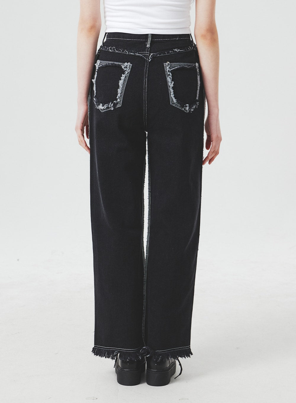 Stitch Detail Jeans BA307 in black, back view on model, wide-fit cotton denim with frayed exposed back pocket edges, contrast stitch side seams, and fringe raw hem detail.