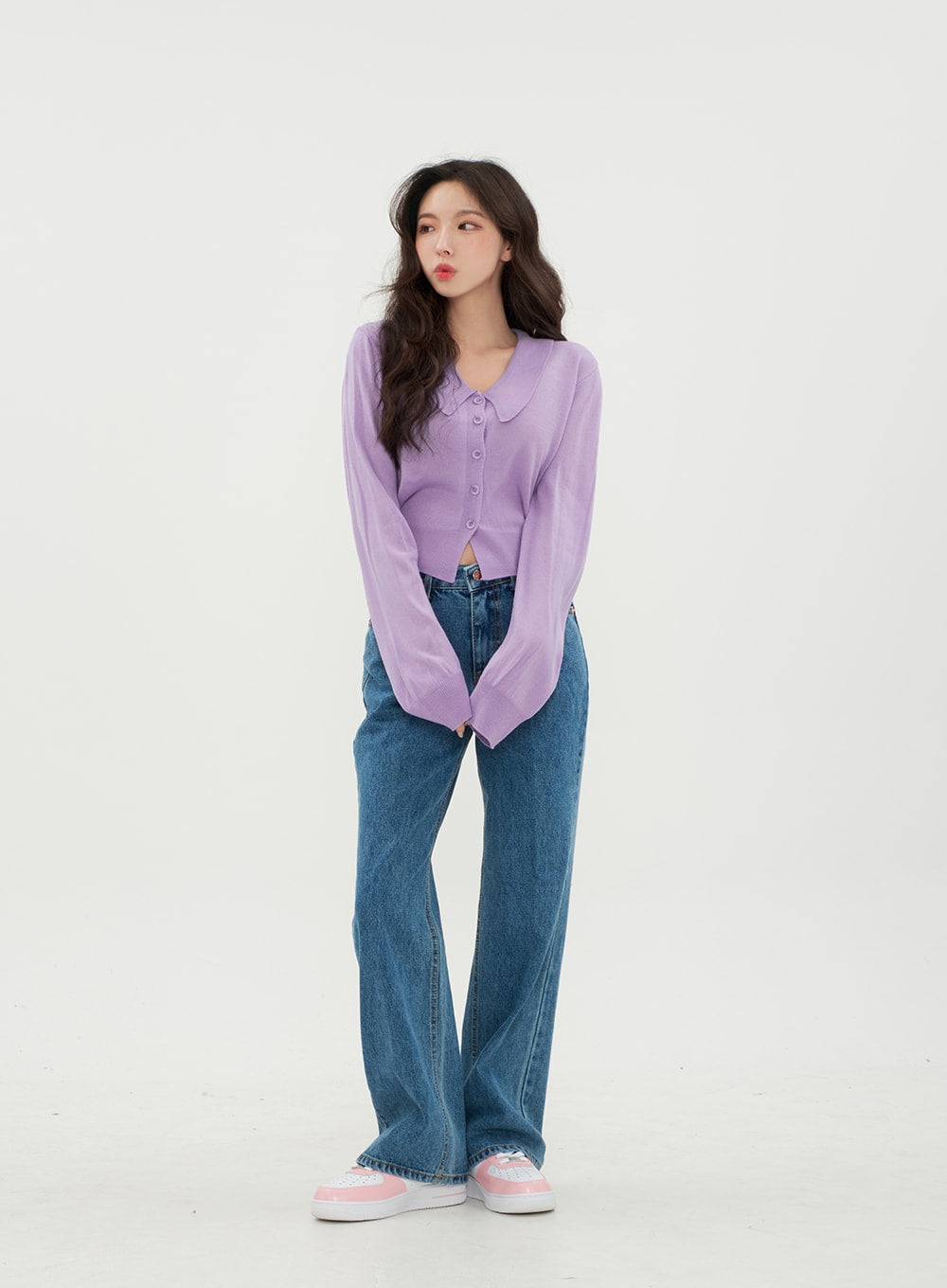 Semi Wide Jeans BM21 in mid-blue denim, front angled shot on model gazing to the side, long wide-fit solid denim with front pockets, styled with lavender cropped cardigan and pink sneakers.