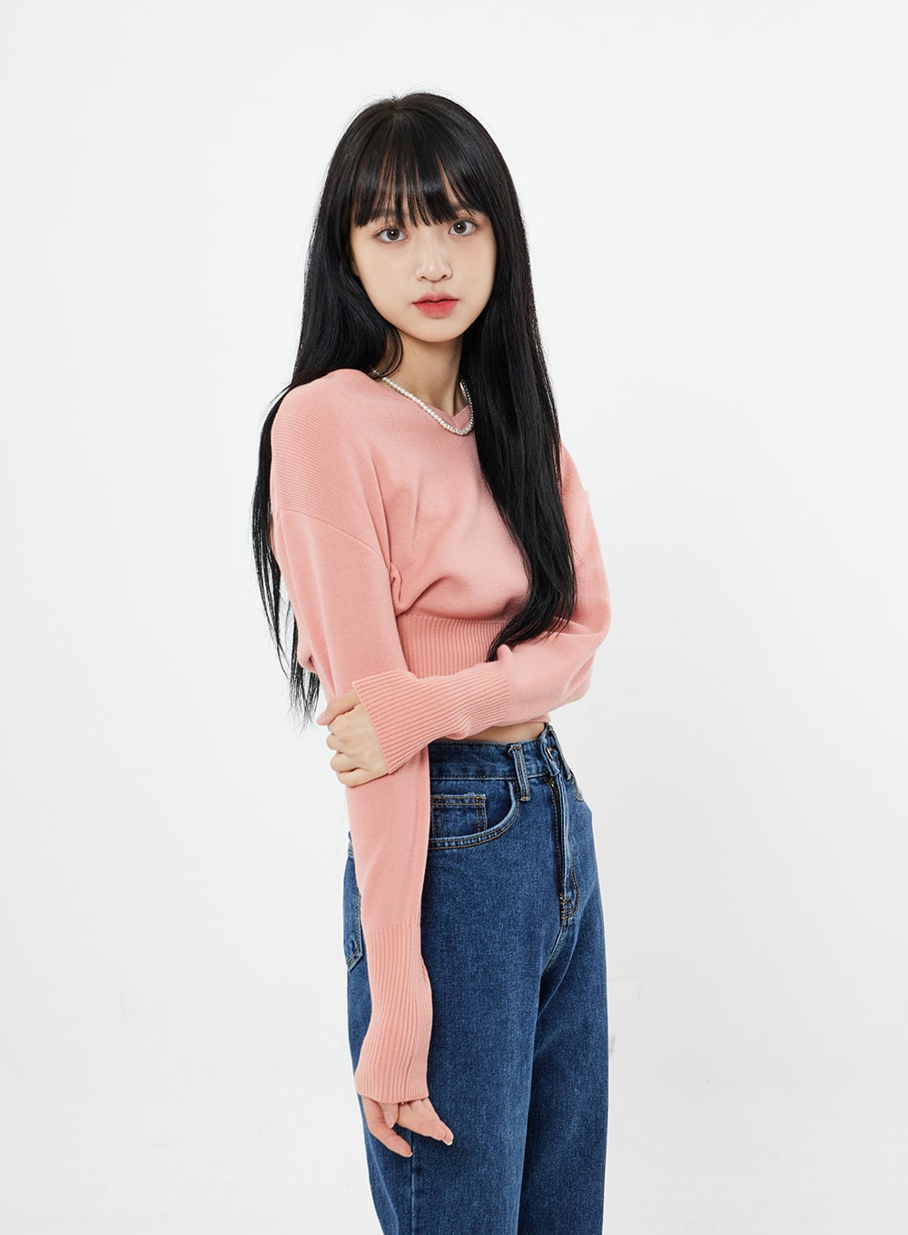Basic Long Denim Pants BS28 in mid-blue, side upper-body shot on model with arms crossed, high-rise waistband and side seam detail visible, cotton denim, pink crop knit.