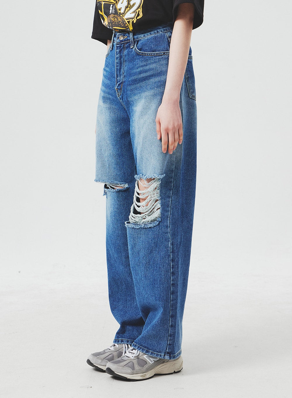 Ripped Knee Blue Jeans BA307 in blue, side-view close-up on model from waist to hem, highlighting large frayed knee rip and wide-leg cotton denim silhouette with faded wash.